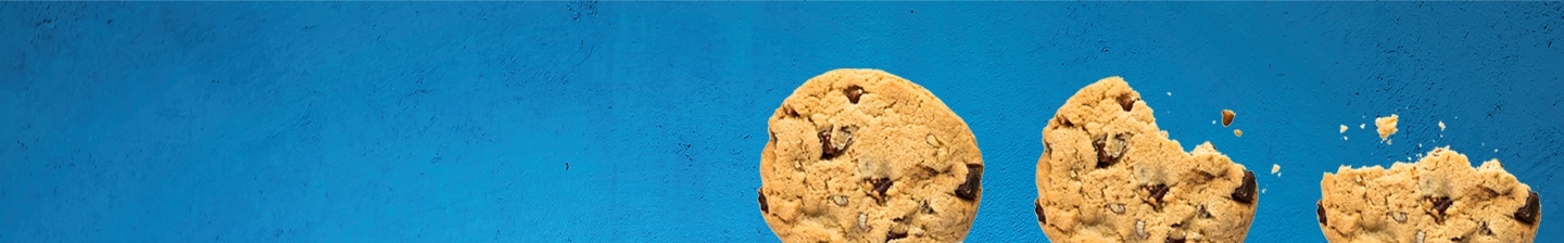 Drie chocolate chip cookies op een blauwe achtergrond, waarvan één gebroken is.
