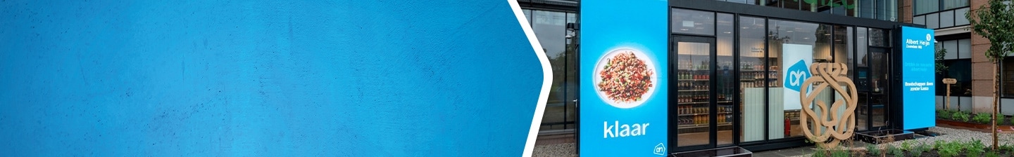 Albert Heijn supermarkt met blauwe banners en ingang, promotie van kant-en-klare maaltijden.