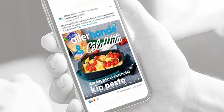 Een persoon houdt een smartphone vast met daarop een recept van Allerhande voor een aardappel-ovenschotel met kip pesto.