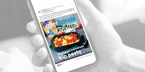 Een persoon houdt een smartphone vast met daarop een recept van Allerhande voor een aardappel-ovenschotel met kip pesto.