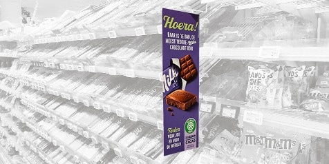 Reclamebord voor Milka-chocolade in een supermarktgang.