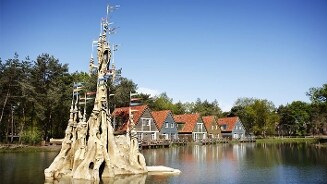 Vakantiehuisjes aan een meer met een indrukwekkend, artistiek beeldhouwwerk op de voorgrond.