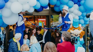 Feestbeeld bij Albert Heijn winkel met veel ballonnen, steltenlopers, veel mensen
