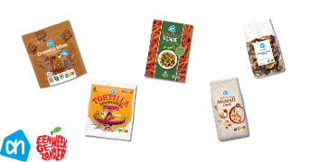 Verschillende Albert Heijn producten, waaronder granola bites choco almond, rode linzen penne, walnoot & vijg notenmix, volkoren muesli naturel en volkoren tortilla met wortel, op een zwarte achtergrond met het Albert Heijn logo en de ‘Een weekje gezonder’ campagne-afbeelding.