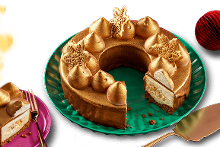 Chocoladetaart met gouden decoraties en kerstvormige versieringen op een groene schaal, geserveerd met een stukje op een paarse schotel.