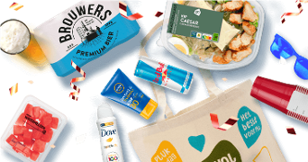 Producten van Albert Heijn, waaronder Brouwers Premium Bier, Caesar kipsalade, watermeloenstukjes, en Dove Invisible Dry deodorant, naast een Red Bull blikje en zonnebrandcrème, rond een canvas tas met feestelijke confetti en zonnebril.