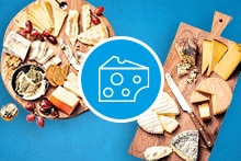 Twee kaastafels met een gevarieerd assortiment kazen, druiven en crackers.