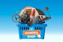 Blauwe winkelmand met het Albert Heijn logo en het voordeelshop-label, gevuld met diverse producten zoals een fiets, barbecue, tuinmeubelen, fitnessapparatuur en een kas.