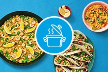 Verschillende gerechten met rijst en zeevruchten, geserveerd met limoenen en taco's.