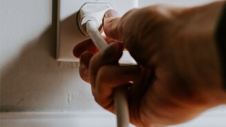 Persoon steekt stekker in een stopcontact