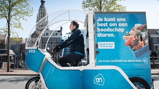 Vrachtfiets van Albert Heijn voor bezorging van boodschappen in een stedelijke omgeving.