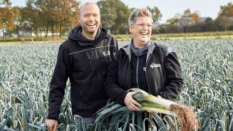 Boeren in een preivel op het veld, waarbij één van de boeren een prei vasthoudt.