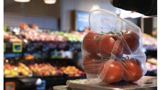 Zak met verse tomaten op een weegschaal in de supermarkt.