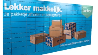 Pakkettenwand met Bol.com dozen en tekst 'Lekker makkelijk. Je pakketje afhalen en terugsturen.' bij Albert Heijn.