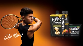 Tennisser met racket in actie naast HiPRO proteïneproducten van Danone op een oranje-zwarte achtergrond met handtekening van Carlos Alcaraz.