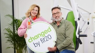 Twee personen poseren in een fitnessstudio met een bord waarop "changed by fit20" staat.