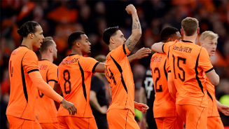 Voetballers in oranje tenue vieren een goal tijdens een wedstrijd, met juichende handgebaren en rugnummers zichtbaar.
