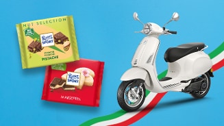 Twee repen Ritter Sport chocolade, smaken pistache en marsepein, naast een witte scooter op een blauwe achtergrond met een Italiaanse vlagstreep.