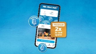 Smartphone met Albert Heijn app op het scherm, waarop spaarkaarten en het glazenzegel spaarprogramma zichtbaar zijn, met een gele sticker 'Premium 2x zo snel sparen' op een blauwe achtergrond