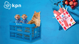 Een blauwe krat van Albert Heijn met twee cartoon hamsters en een kat erin, naast een verpakking AH Aardbei IJsjes en fruit op een blauwe ondergrond, met linksboven het KPN-logo.