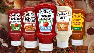 Heinz sauzen, waaronder ketchup, patat saus en curry, staan op een eettafel met diverse gerechten