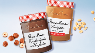 Bonne Maman hazelnootpasta en pindapasta met stukjes pinda in glazen potten, omringd door hazelnoten en pinda's.