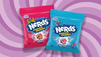 Twee zakjes Nerds Gummy Clusters snoep in de smaken fruits en berries op een paars-gekruld achtergrond.