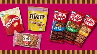 Assortiment van populaire chocoladeproducten, waaronder Maltesers White, peanut M&M's, verschillende KitKat repen en Dan's Bake Sale koekreep op een roze achtergrond