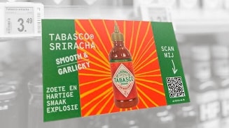 Promotiebord van Tabasco Sriracha saus met tekst "Smooth & Garlicky" en "Zoete en hartige smaakexplosie", inclusief QR-code en prijs.