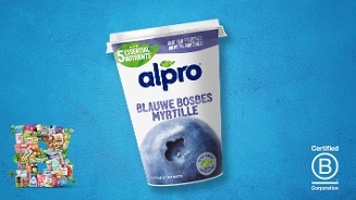 Alpro Blauwe Bosbes sojayoghurt op een blauwe achtergrond, met een afbeelding van een grote bosbes en labels voor essentiële voedingsstoffen en B Corp certificering.