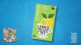 Doos Clipper Lemon Organic Green Tea op een blauwe achtergrond met Fairtrade en biologische keurmerken, plus B Corporation certificaat.
