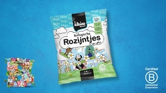 Zakje De Kleine Keuken biologische rozijntjes zonder sulfiet tegen een blauwe achtergrond, met Certified B Corporation logo rechts en een collage van diverse producten linksonder.
