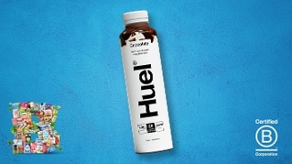 Fles Huel Chocolate kant-en-klare maaltijd op een blauwe achtergrond, met links kleine verpakkingen van diverse producten en rechts het Certified B Corporation logo.
