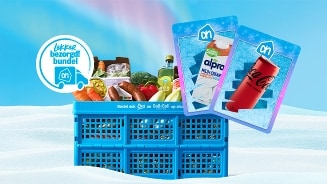 Blauwe krat met diverse boodschappen zoals groenten, fruit, olie en frisdrank, afgebeeld met een 'lekker bezorgd! bundel' label en bonuskaarten van Alpro en Coca-Cola, op een lichte achtergrond met sneeuwmotief.