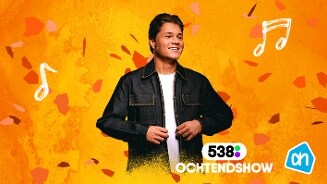 Man in een donker jack op een oranje achtergrond met muzieknoten, logo van 538 Ochtendshow en Albert Heijn.