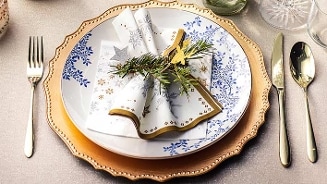 Feestelijk gedekte tafel met sierlijk servies, servet en bestek.