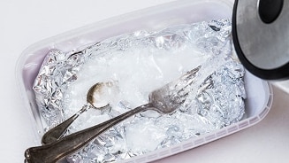 Reinigingsproces voor zilver bestek met aluminiumfolie en kokend water in een plastic bakje