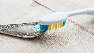 Tandenborstel met tandpasta op een zilveren lepel