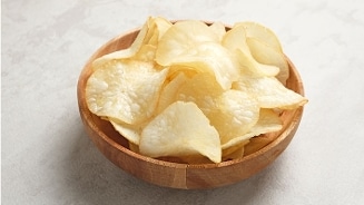 Kom chips in een houten kom op een lichtgekleurde ondergrond