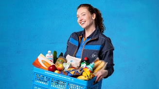 Vrouwelijke ah bezorgster met een krat vol eten en drinken
