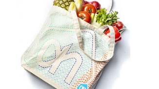 Herbruikbare Albert Heijn boodschappentas gevuld met diverse verse groenten en fruit, waaronder ananas, bananen, tomaten en sla.