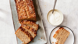 Bananenbrood op een schaal met yoghurt in een schaaltje ernaast.