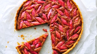 Rabarbertaart met een stuk eruit gesneden op bakpapier.