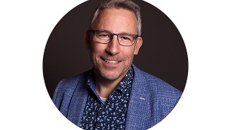 Profielfoto van Arie met een geblokkeerd gezicht, in een blauw colbert en een donkerblauw hemd met patroon.