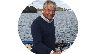 Man bij een waterlandschap met een fiets.