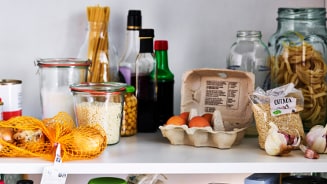 Keukenkast gevuld met diverse ingrediënten zoals eieren, quinoa, knoflook, pasta, en kruiden.