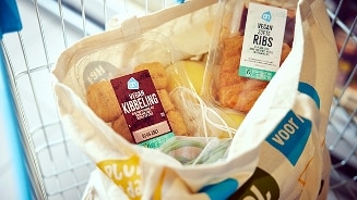 Een boodschappentas in een winkelwagentje met daarin AH vegan kibbeling en AH vegan zoete ribs.