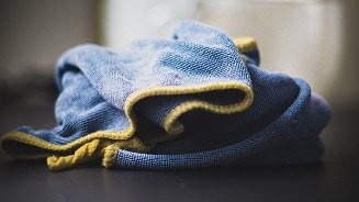 Blauwe schoonmaakdoek met gele rand op een donker oppervlak