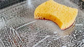 Gele spons op een ingezeepte bakplaat