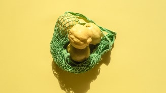 Kweeperen in een groen netje op een gele achtergrond